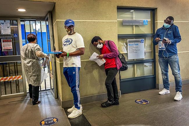 People who were just tested for COVID-19 wait in line to make payment for the test at a private laboratory in Johannesburg, South Africa, Saturday Dec. 19, 2020. South Africa is bracing for its second wave, as many people will travel across provinces for vacations and visiting their families. (AP Photo/Jerome Delay)
