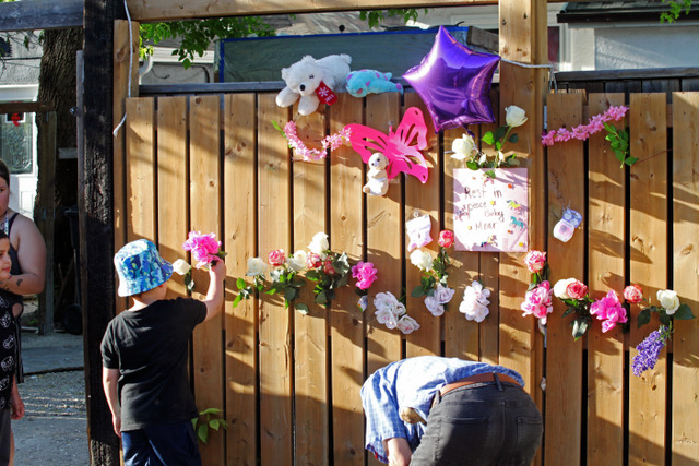 ERIK PINDERA/WINNIPEG FREE PRESS
A child places a flower into the fence at the vigil in the alley behind Boyd Avenue Wednesday.