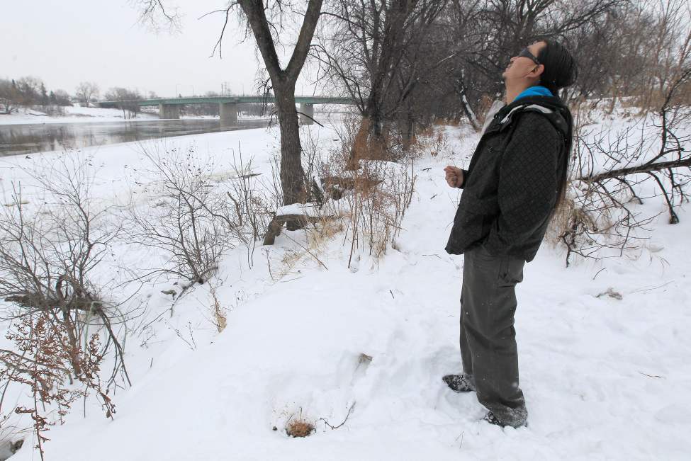 JOE BRYKSA/WINNIPEG FREE PRESS
Father Daniel Thorassie reflects after offering tobacco on the south shore of the Red River where his six-year-old son fell through the ice and is presumed drowned.
December 5, 2010