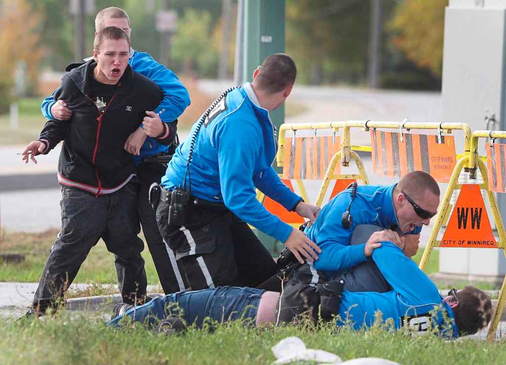 Winnipeg police cadets restrain two men from a tow truck after they burst through police lines at the scene of a double fatal motor vehicle crash involving another tow truck on Dugald Road near Plessis Road.