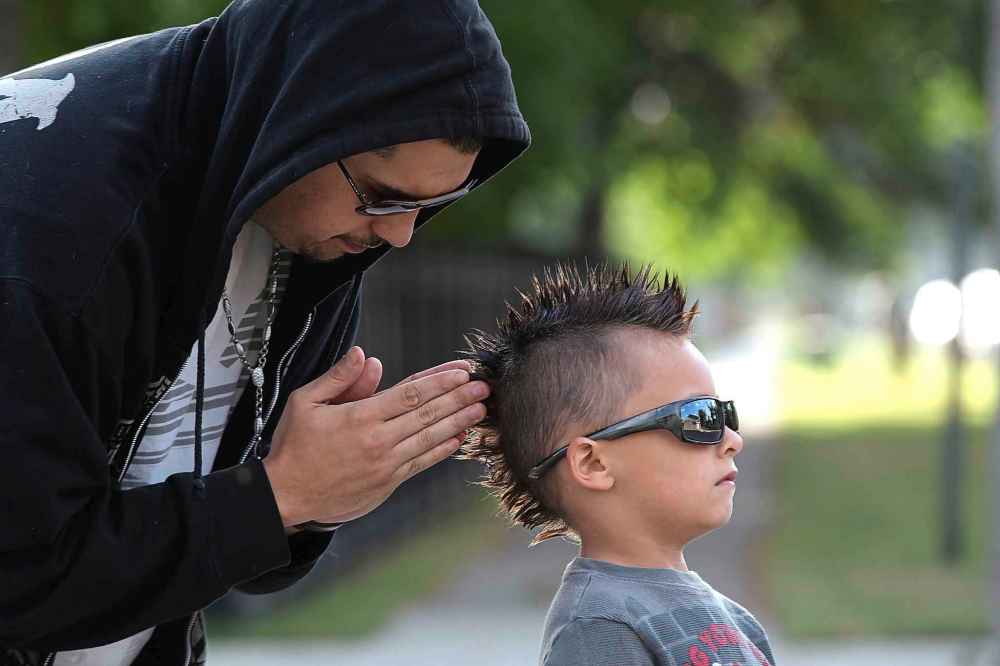 Father Jose Recabarren does some last-minute adjustments on his son Saint Recabarren's mowhawk haircut before the first day of school in 2013.