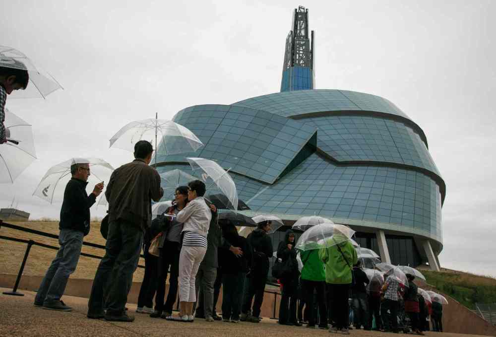 Melissa Tait / Winnipeg Free Press
Visitors wait in the rain, with supplied umbrellas, for their preview tours at the Canadian Museum for Human Rights on Saturday. The rain kept away some of the people with reserved tickets, allowing walk-ups to gain access to the guided tour of four of 11 galleries. The rest of galleries open Sept. 27.