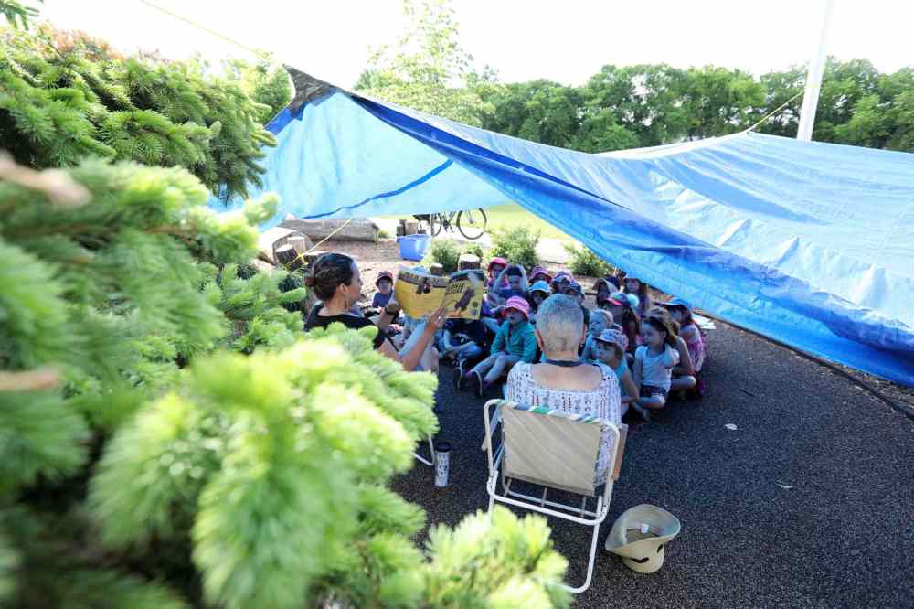 Students study in the shade of a tarp.