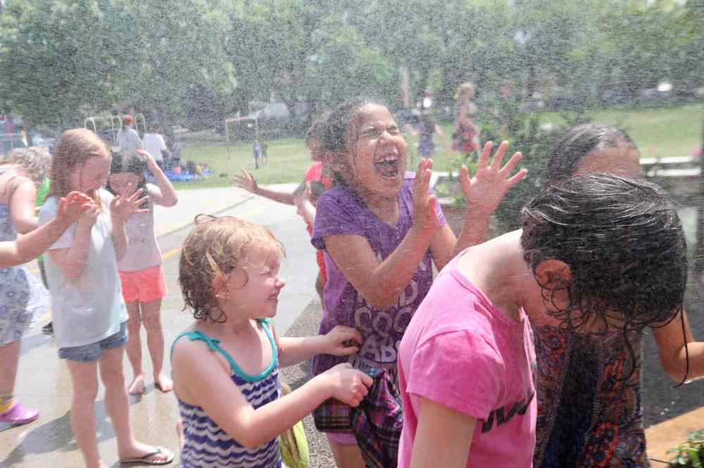 Students refresh themselves in sprinkler during recess.