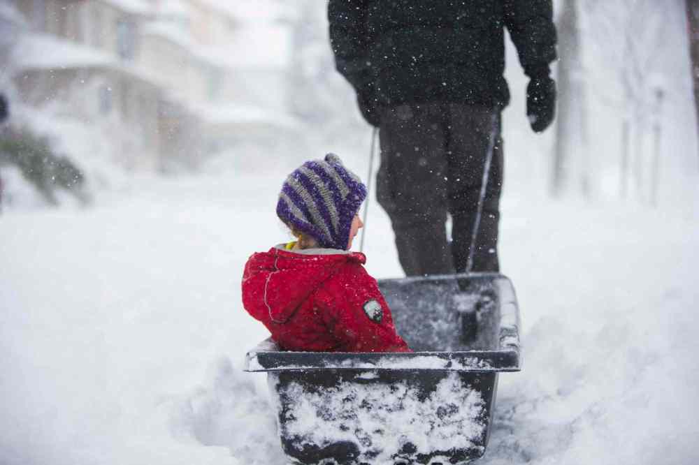 Sydney Cumming, four, gets pulled down the sidewalk in a sled by her dad, Andy Cumming, in Winnipeg. (Mikaela MacKenzie / Winnipeg Free Press)