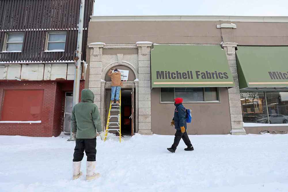 Steve Swiderski hangs new sign on the former Mitchell Fabrics building.