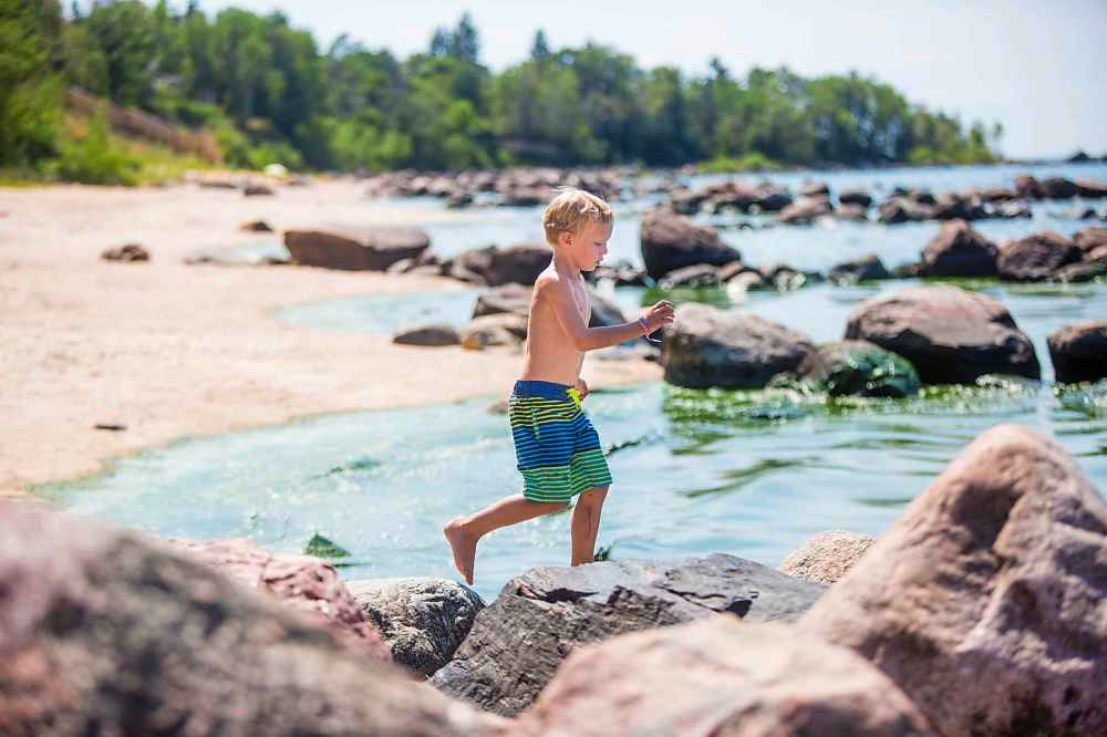 Shea Keast, six, plays on the rocks next to the algae bloom at Connaught Beach.