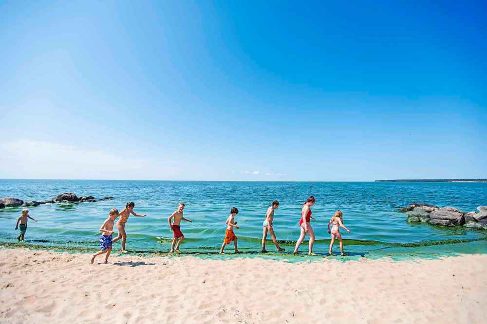 Kids walk along the edge of the algae-laden water at Connaught Beach in Victoria Beach Thursday.