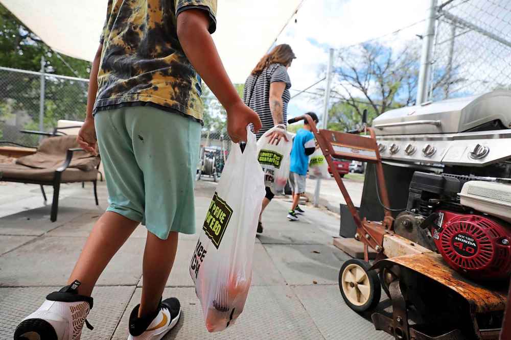 A young mother and her two kids leaves with her kids carrying plastic bags full of fresh fruits and vegetables their mother purchased at the Indigenous Family Centre's market.