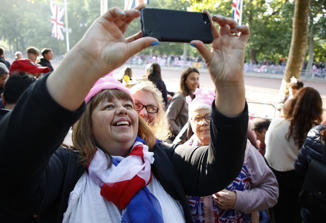 Royal fans take a selfie as they stand alongside the Mall leading to Buckingham Palace in London, Thursday June 2, 2022, on the first of four days of celebrations to mark the Platinum Jubilee. The events over a long holiday weekend in the U.K. are meant to celebrate the monarch's 70 years of service. (AP Photo/David Cliff)