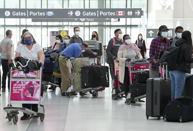 People wait in line to check in at Pearson International Airport in Toronto on Thursday, May 12, 2022.Transport Minister Omar Alghabra says the federal government is working on new measures to help ease the issues at major airports, adding that a