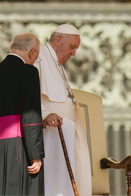 Pope Francis is helped by his aide, Monsignor Leonardo Sapienza, left, as he arrives with a cane to attend his weekly general audience in St. Peter's Square at The Vatican, Wednesday, June 8, 2022. (AP Photo/Alessandra Tarantino)
