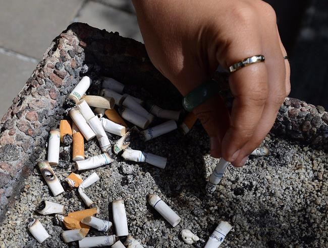 A smoker puts out a cigarette in a public ash tray in Ottawa on Tuesday, May 31, 2016. Canada is poised to become the first country in the world to require that a warning be printed on every cigarette. THE CANADIAN PRESS/Sean Kilpatrick