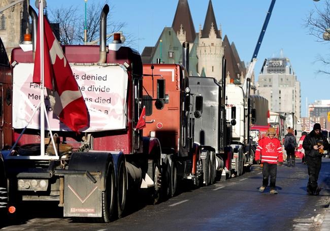 A person wears a Team Canada hockey jersey as Wellington Street is lined with trucks once again after city officials negotiated to move some trucks towards Parliament and away from downtown residences, on the 18th day of a protest against COVID-19 measures that has grown into a broader anti-government protest, in Ottawa, on Monday, Feb. 14, 2022. THE CANADIAN PRESS/Justin Tang