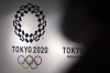 FILE - A person walks near Tokyo 2020 logo in Haneda Airport on June 14, 2021, in Tokyo. Tokyo Olympic officials, meeting Tuesday, June 21, 2022, before the body is dissolved at the end of the month, were to detail the final numbers that were driven up by the pandemic, but were in record range even before that. (AP Photo/Eugene Hoshiko, File)