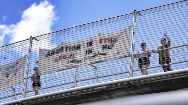 Volunteers with the Triangle Abortion Access Coalition wave to cars passing under the American Tobacco Trail Bridge over Interstate 40 in Durham, N.C., Friday, June 24, 2022, the afternoon that the Supreme Court decision overturning Roe v. Wade was handed down. The volunteers are occupying the bridge throughout the day.