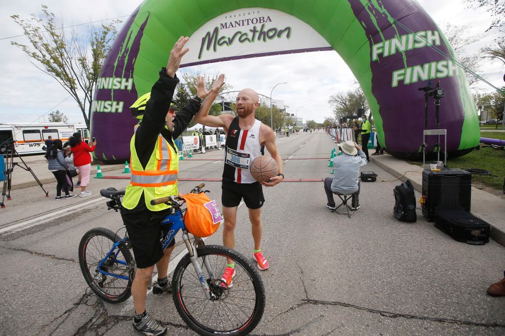 JOHN WOODS / WINNIPEG FREE PRESS
Steffan Reimer gets a high five after crossing the finish line at the Manitoba Marathon. Reimer dribbled a ball for the full marathon.