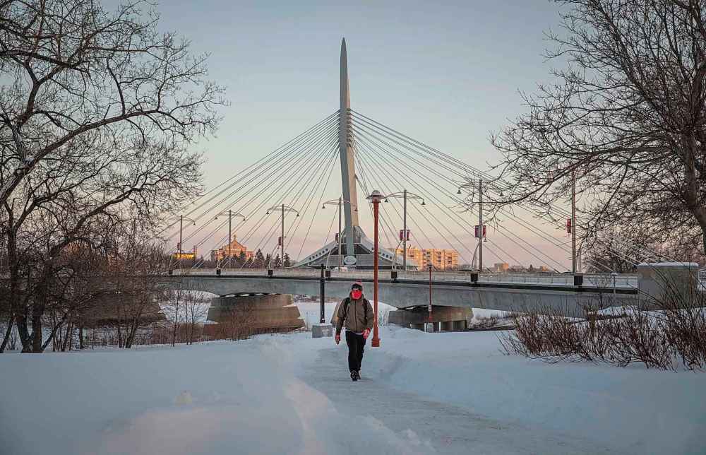 JESSICA LEE / WINNIPEG FREE PRESS
Braeden Mitchell walks on the path under the Provencher Bridge after snowy skies cleared around sunset on Tuesday.