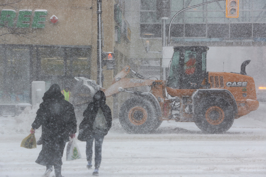 MIKE DEAL / WINNIPEG FREE PRESS
Pedestrians cross Portage Avenue during heavy snowfall while front-end loaders clear snow Wednesday morning.