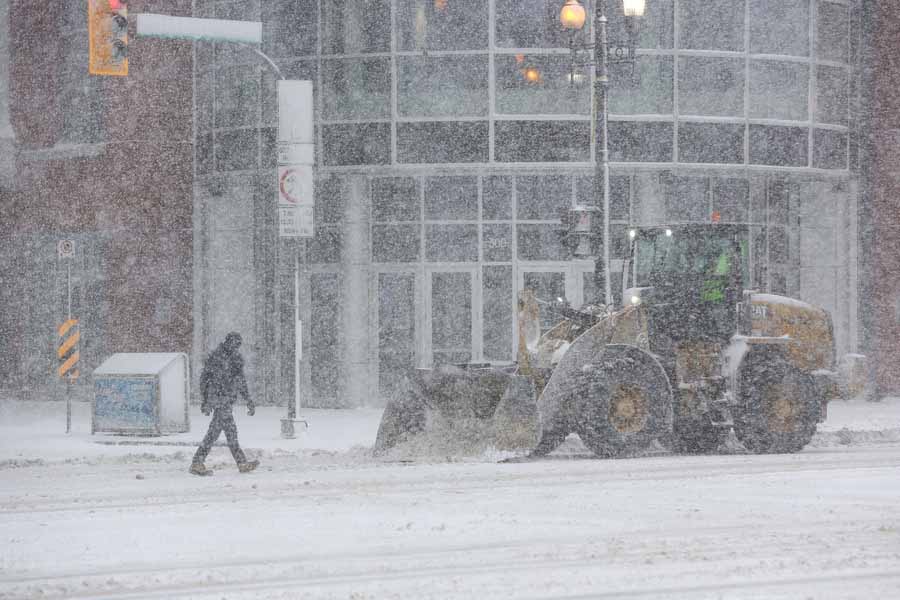MIKE DEAL / WINNIPEG FREE PRESS
A pedestrian crosses Donald Street during heavy snowfall while -frontend loaders clear snow Wednesday morning.