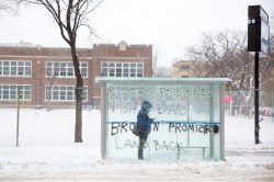 A person waits in a graffitied bus stop on Maryland Street, Thursday morning. (Mike Deal / Winnipeg Free Press)