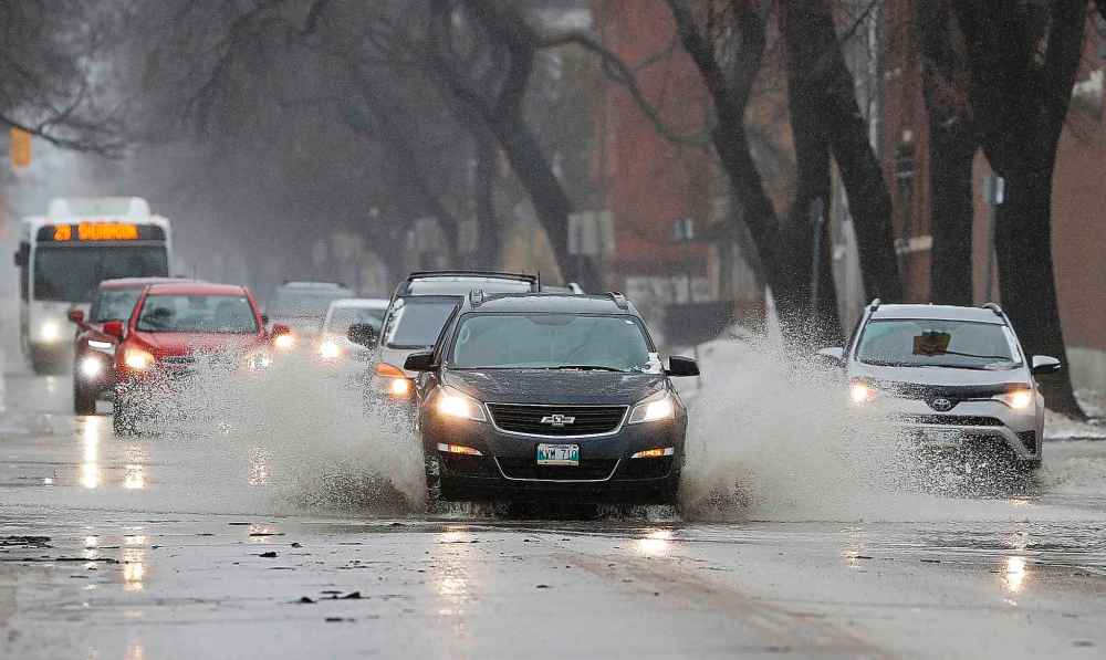 Drivers try to minimize their speed as they drivers through large puddles of water on Sherbrook Street Sunday. (John Woods / Winnipeg Free Press)