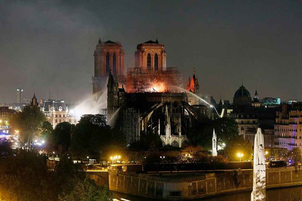 Firefighters tackle the blaze as flames and smoke rise from Notre Dame cathedral. (Thibault Camus / The Associated Press)