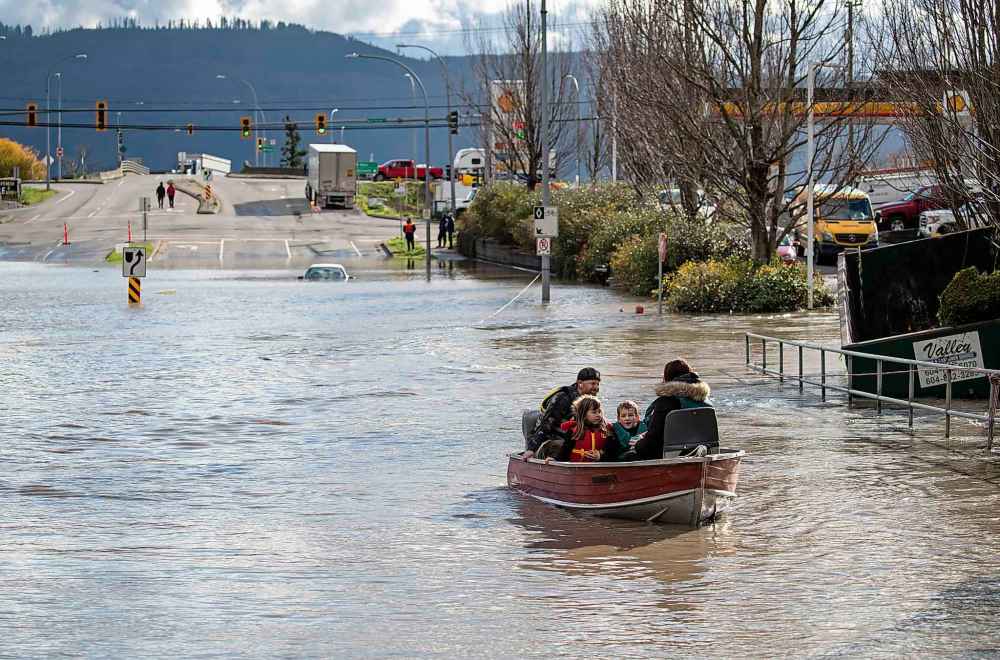 CP
A woman and children who were stranded by high water due to flooding are rescued by a volunteer operating a boat in Abbotsford, B.C., on Tuesday, November 16, 2021. THE CANADIAN PRESS/Darryl Dyck