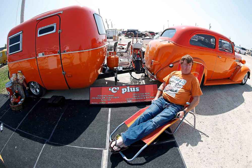 J.J. McColm relaxes outside his orange themed trailer and car.