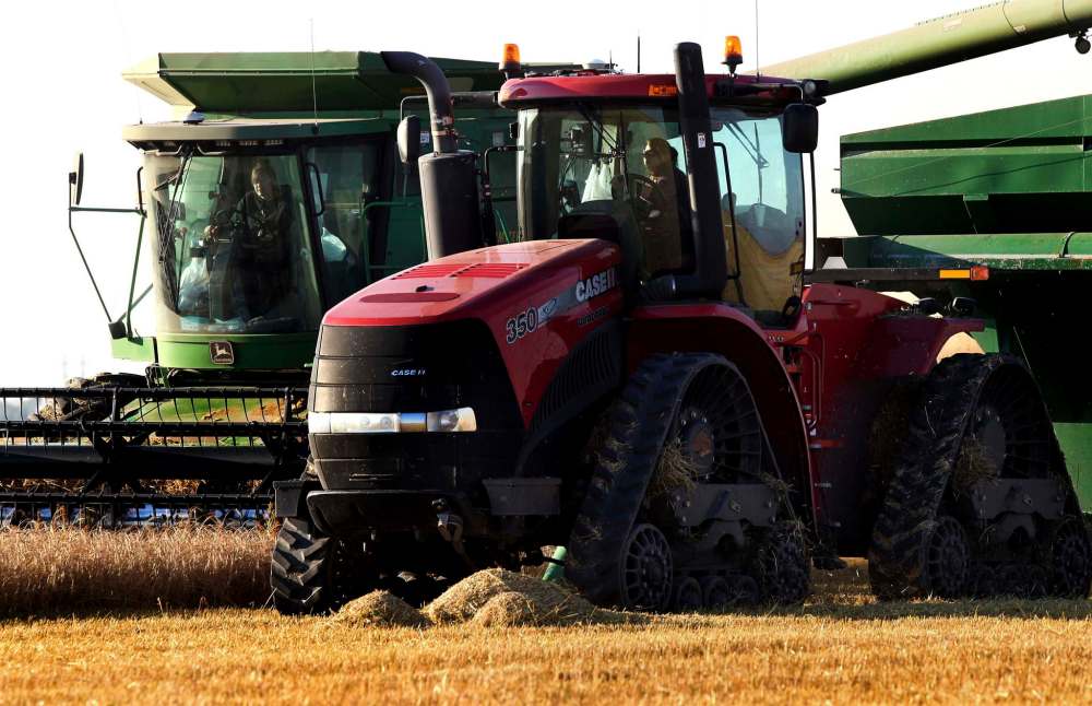 Kaylie Anderson (right) drives the wheat cart alongside a combine operated by her sister Kara.