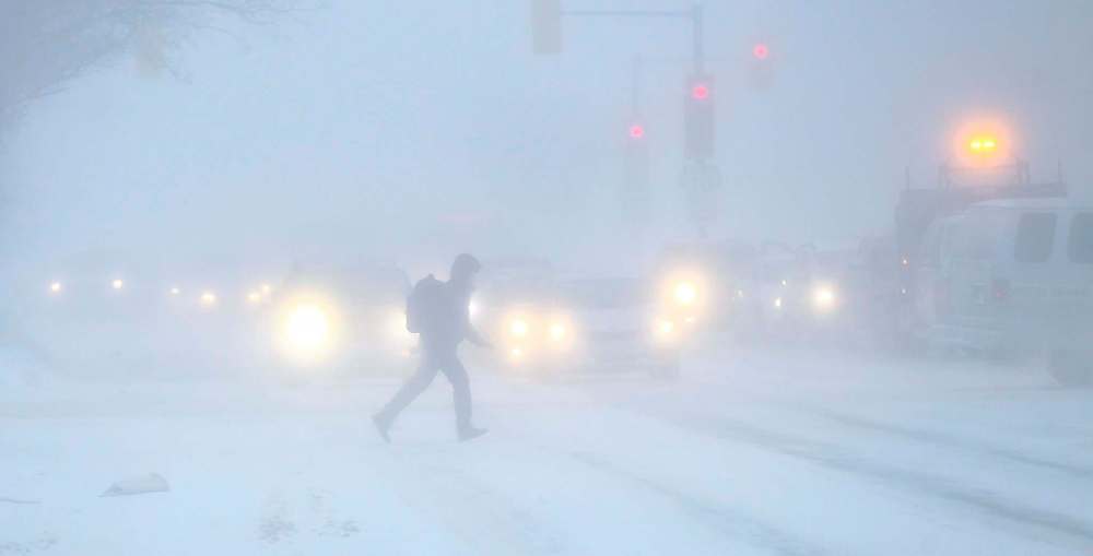 A pedestrian dashes across Portage Avenue at Maryland Street on Jan. 12, 2017 as high winds cause blowing snow. (Mike Deal / Winnipeg Free Press files)
