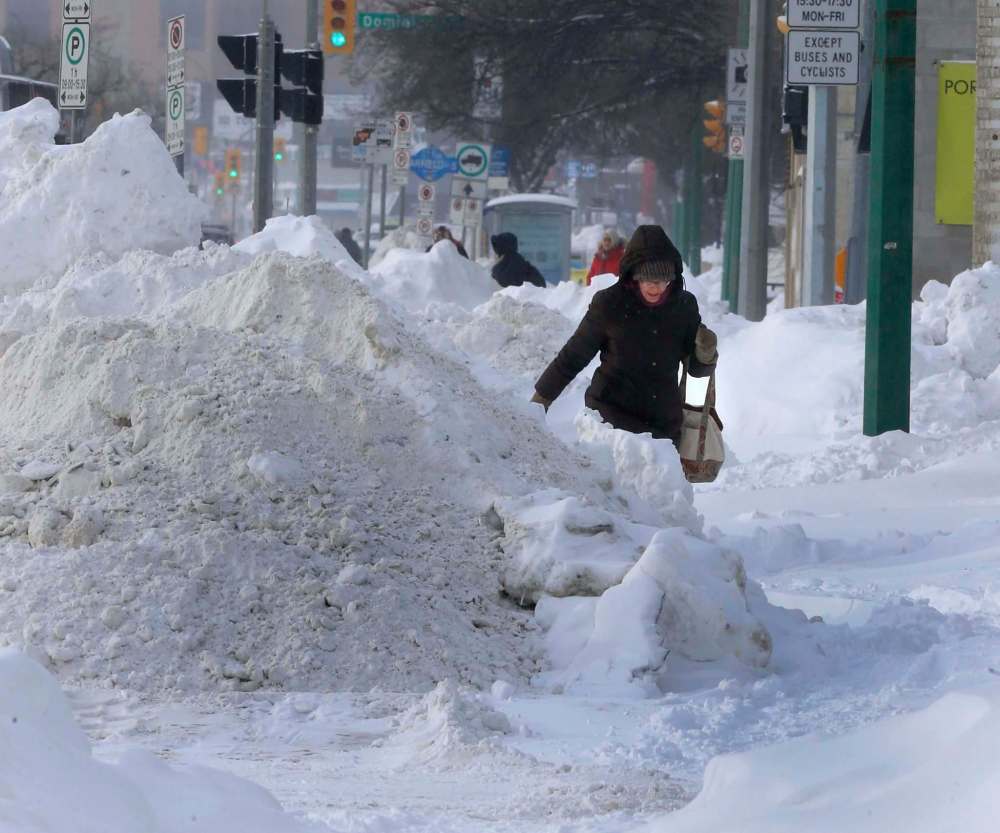 A woman navigates along a snow-filled sidewalk on Portage Avenue near Sherburn Street on Jan. 3, 2017. (Wayne Glowacki / Winnipeg Free Press)