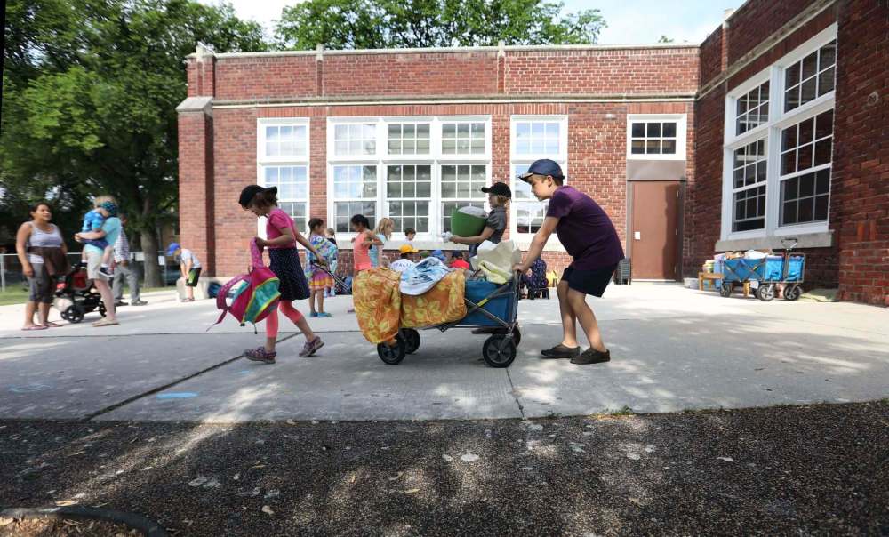 Students wheel their supplies outside in a wagon at the start of the day.