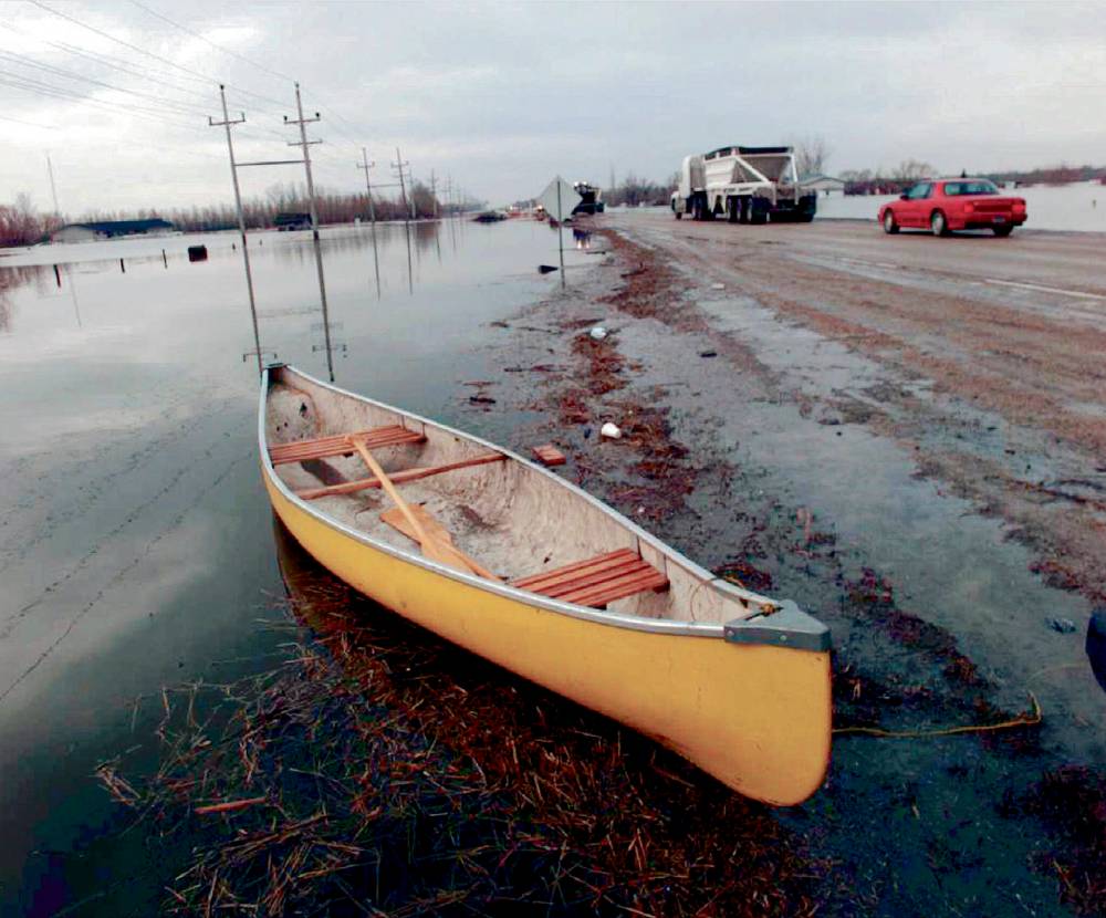 A canoe sits on the side of Highway 59 as traffic continues to travel the flood-soaked road. (Beth A. Keiser / The Associated Press files)