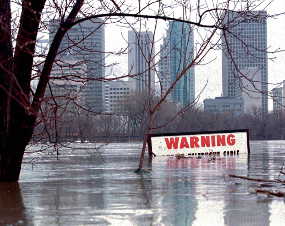 A warning sign sits almost completely submerged by the flood waters of the Red River near downtown Winnipeg in April 1997.(Tom Hanson / The Canadian Press files)