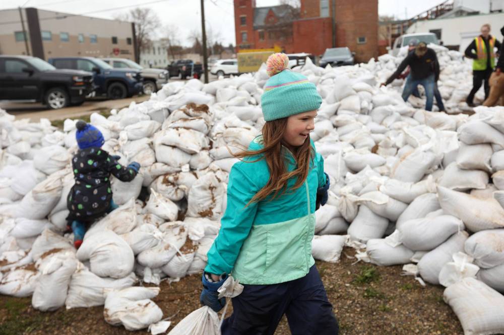All hands on deck: nine-year-old Adriana Jacobson helps load sandbags into a truck in Minnedosa. (Tim Smith / The Brandon Sun)