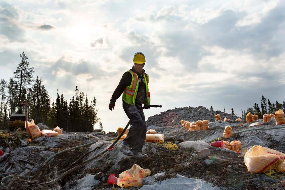 ANDREW RYAN / WINNIPEG FREE PRESS
Jim Sinclair hauls a water pump hose amongst bags of explosives on Aug. 26.