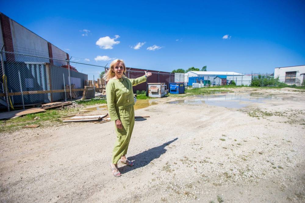 MIKAELA MACKENZIE / WINNIPEG FREE PRESS
Janeen Junson, owner of Artists Emporium, points out neighbouring lots with unpaved parking areas in the back lot of their new location in Winnipeg. The city says they have to pave a gravel parking lot before they open at their new location.