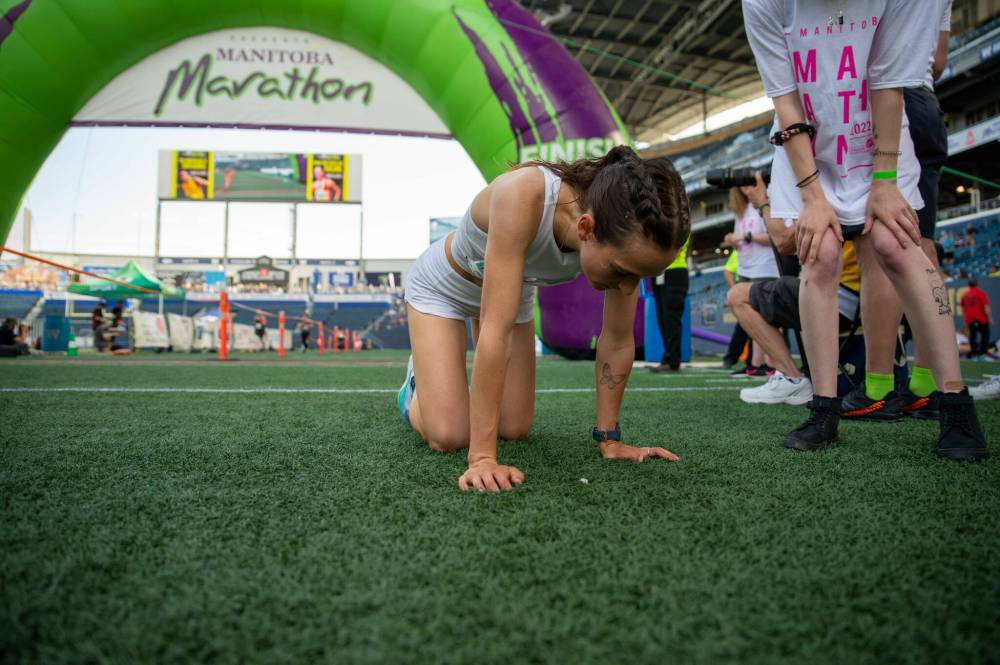 ETHAN CAIRNS / WINNIPEG FREE PRESS FILES
A runner falls to her knees after crossing the finish line of the half marathon at IG Field Sunday.