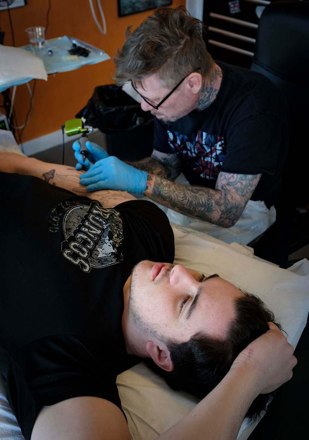 Mike Peace works on Ryan Straschnitzki’s tattoo to honour the fallen. (Jeff McIntosh / The Canadian Press)