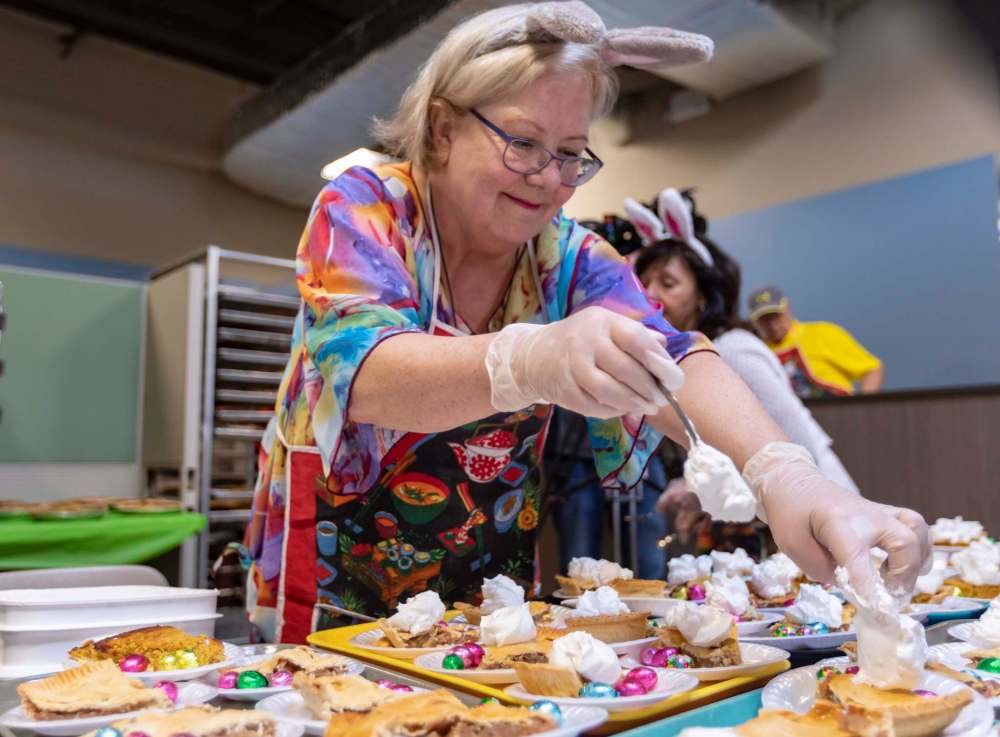 Volunteers help prepare and serve the annual Easter meal hosted by Siloam Mission Monday.