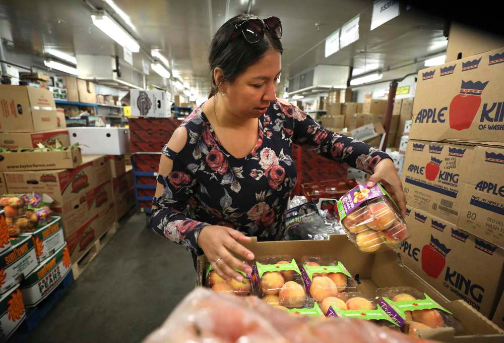 McDonald looks over the quality and quantity of a crate of fresh peaches in the walk-in fridge at Sobeys.