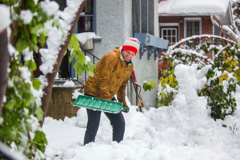 MIKAELA MACKENZIE / WINNIPEG FREE PRESS
Nathan Dueck shovels wet, heavy snow in Wolseley on Saturday.