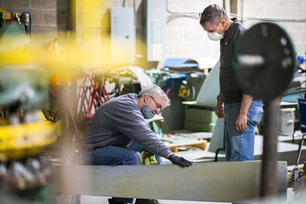 Matt Halpin (left) and Marsh Pettitt work on restoring a propeller.