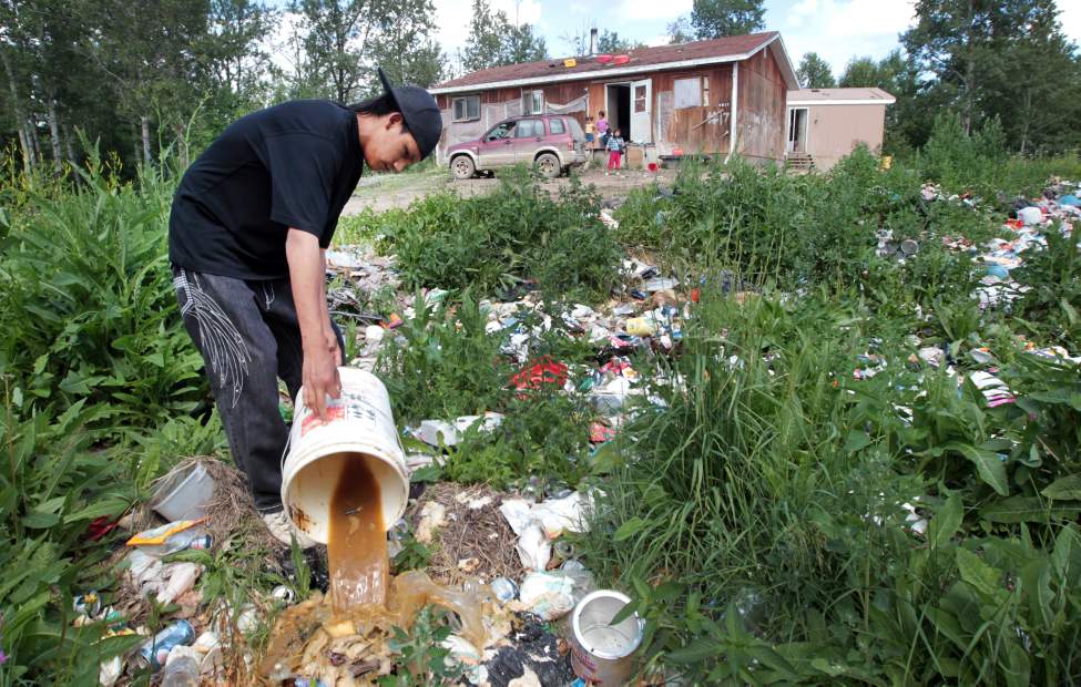 JOE BRYKSA/WINNIPEG FREE PRESS
NO RUNNING WATER FEATURE
Solomon McPherson dumps a slop pail full of sewage in a makeshift dump just outside their home at Garden Hill First Nation. The family lives in this home with no running water. July 2010