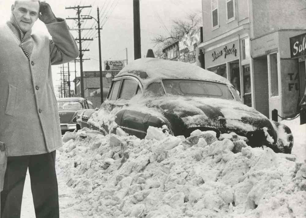 A man appears perplexed about what do do with a car plowed under on Osborne Street. (Bill Rose / Winnipeg Free Press Archives)