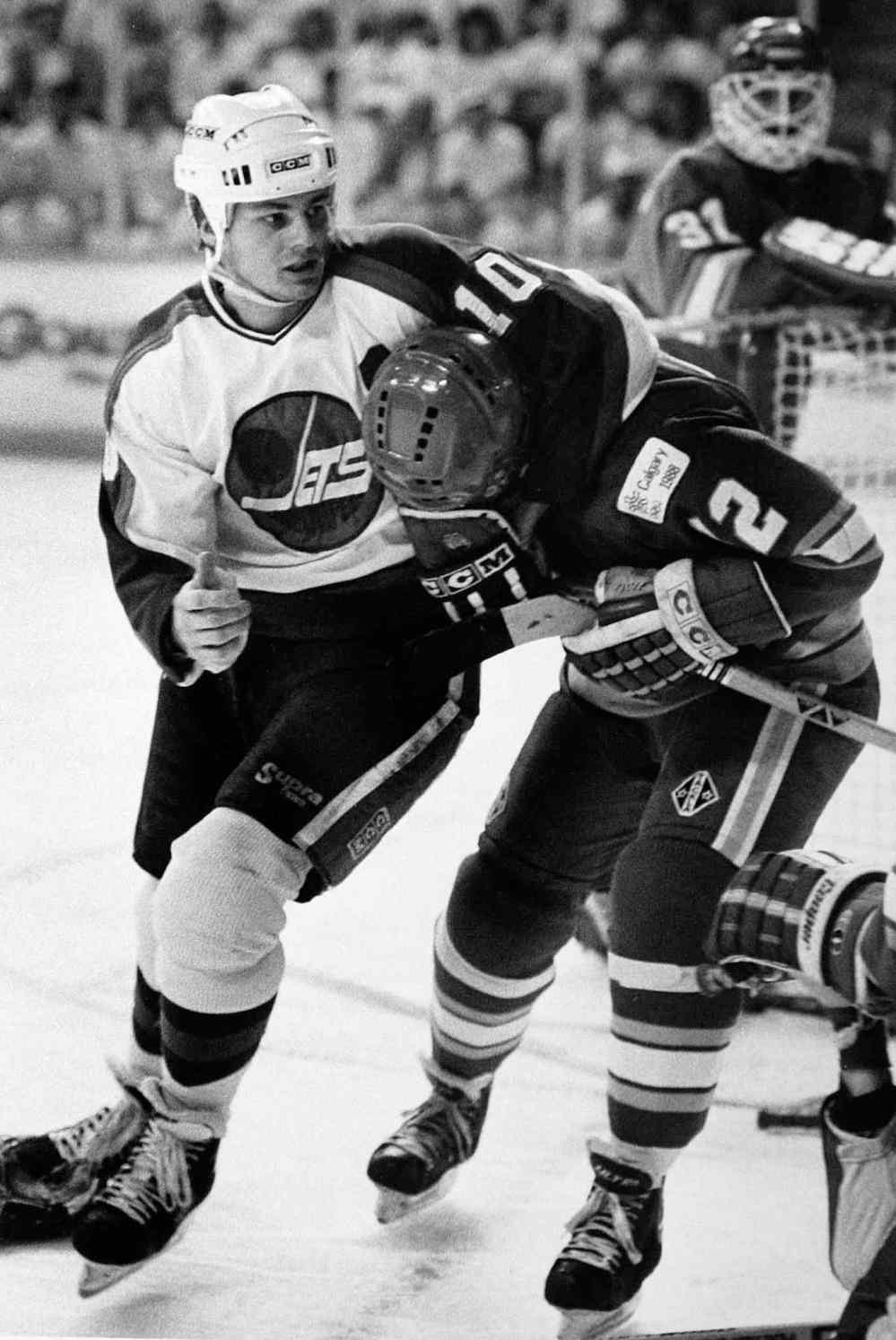 Hawerchuk grabs Calgary Flames forward Haken Loob with Flames goalie Rejean Lemelin looking on in a game on May 17, 1990. (Winnipeg Free Press files)