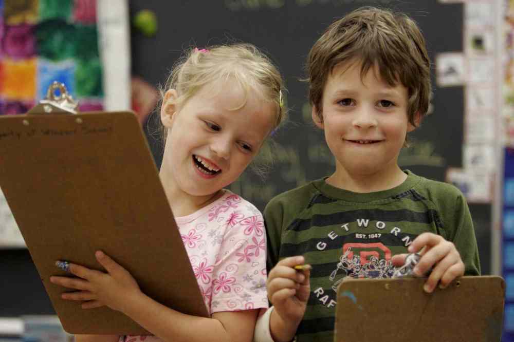 Kindergarten: Hailey (from left) and Devon Mcleod walk around classroom writing down words they recognize. (Joe Bryksa / Winnipeg Free Press)