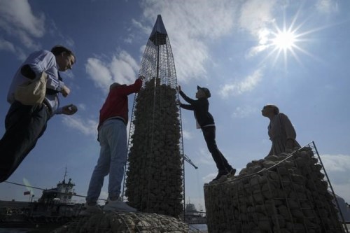 FILE - People build a model of the business tower Lakhta Centre, at the headquarters of Russian gas monopoly Gazprom, filling the frame with stones, in St. Petersburg, Russia, Thursday, June 9, 2022. It's not a summer heat wave that's making European leaders and businesses sweat. It's fear that Russia's manipulation of natural gas supplies will lead to an economic and political crisis next winter. Or, in the worst case, even sooner. (AP Photo/Dmitri Lovetsky, File)