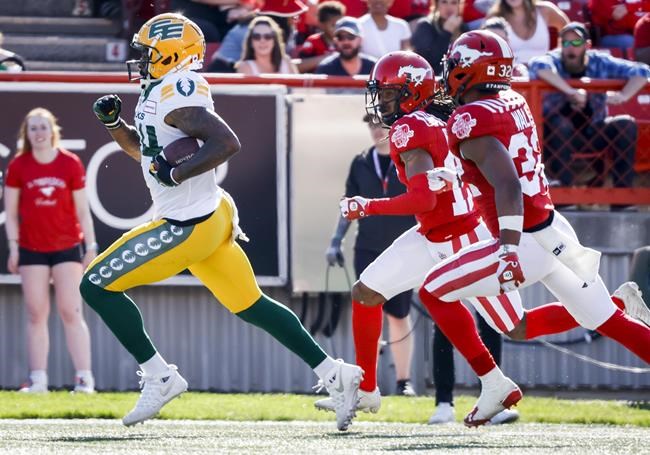 Edmonton Elks receiver Emmanuel Arceneaux, left, runs in a touchdown as Calgary Stampeders defensive back Dionte Ruffin, centre, and defensive back Titus Wall chase him during first half CFL football action in Calgary, Saturday, June 25, 2022. THE CANADIAN PRESS/Jeff McIntosh
